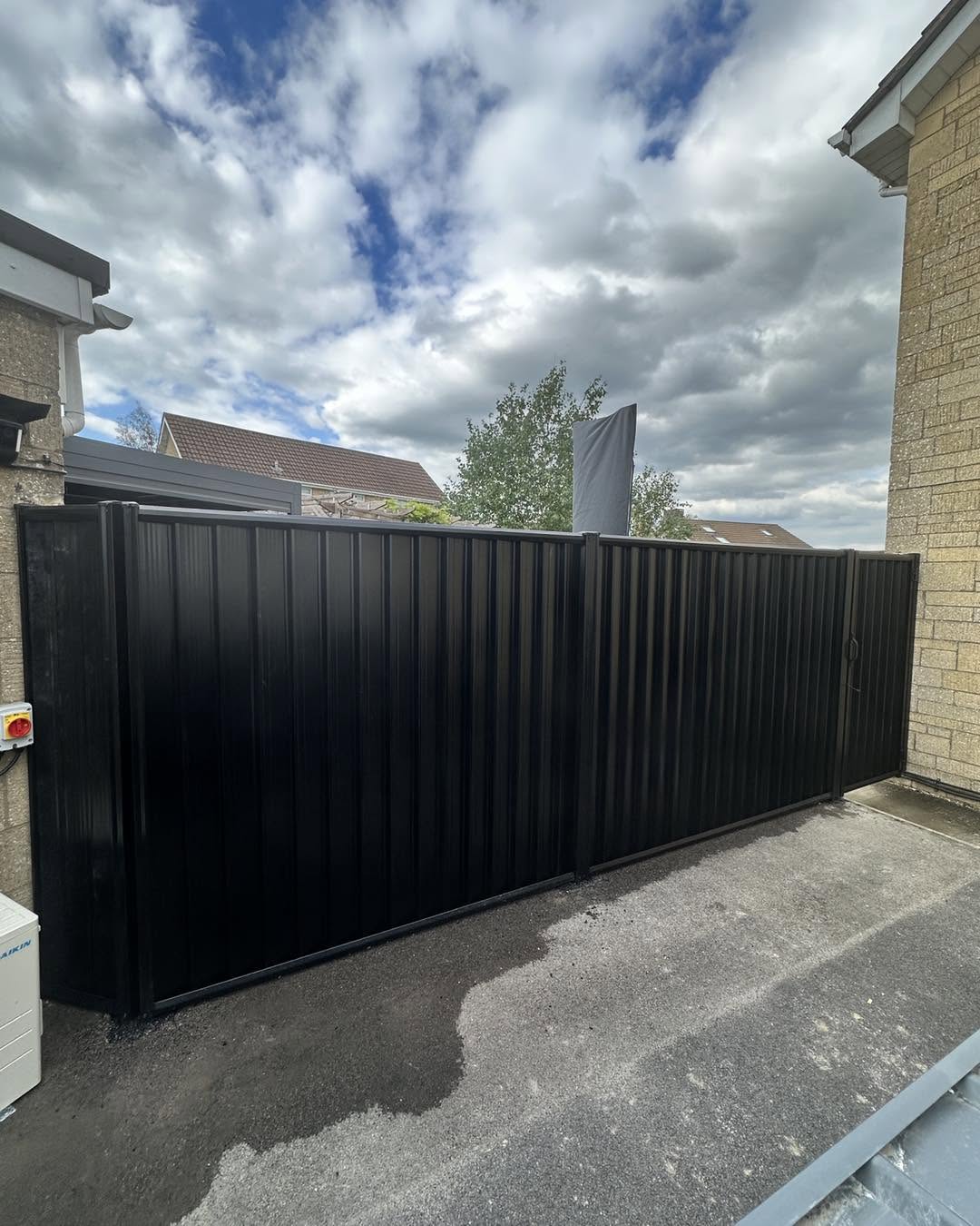 Black metal double driveway gates with a matching fence panel