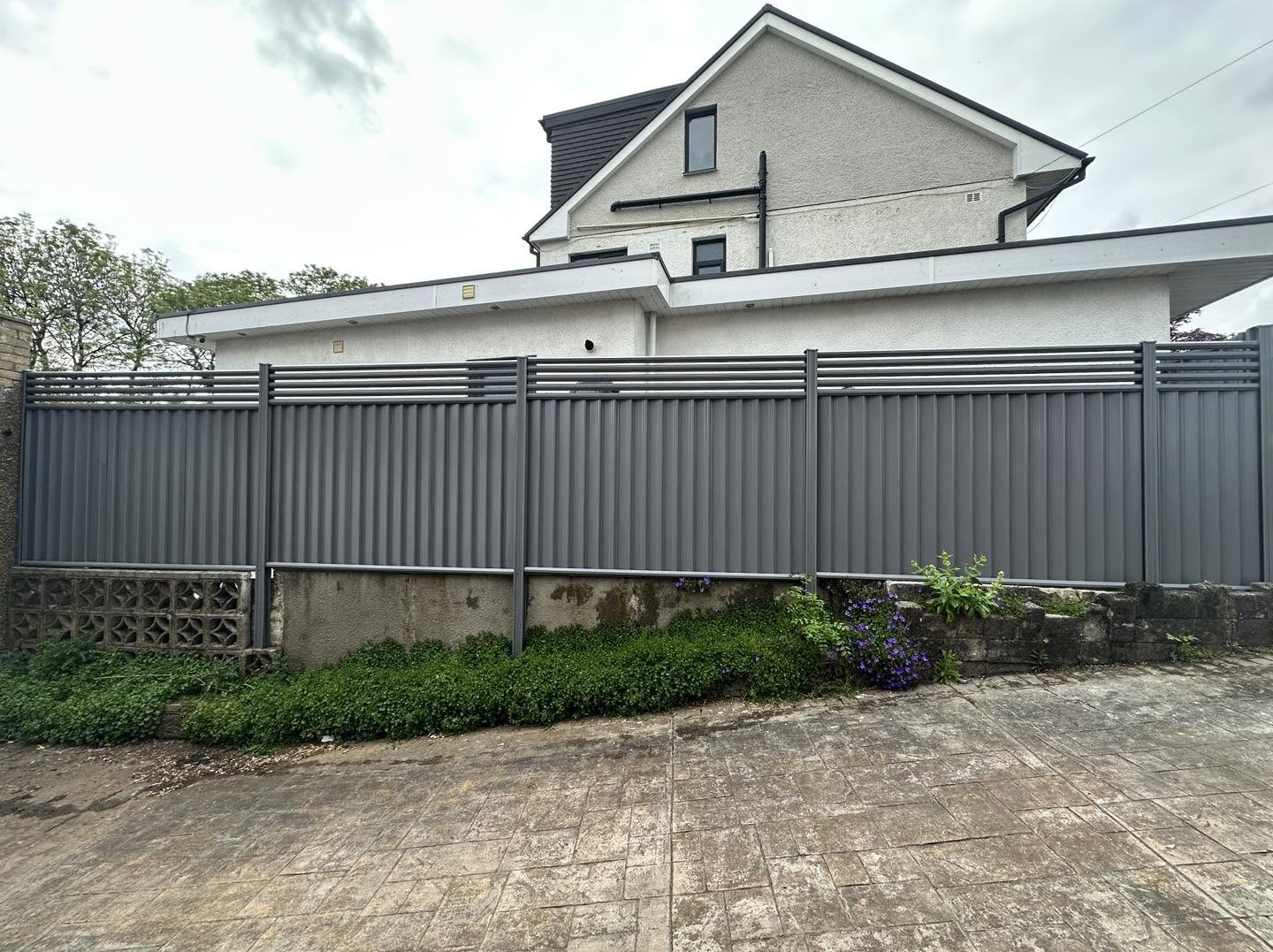 Modern anthracite grey composite and metal fencing with a louvred slat top along a driveway