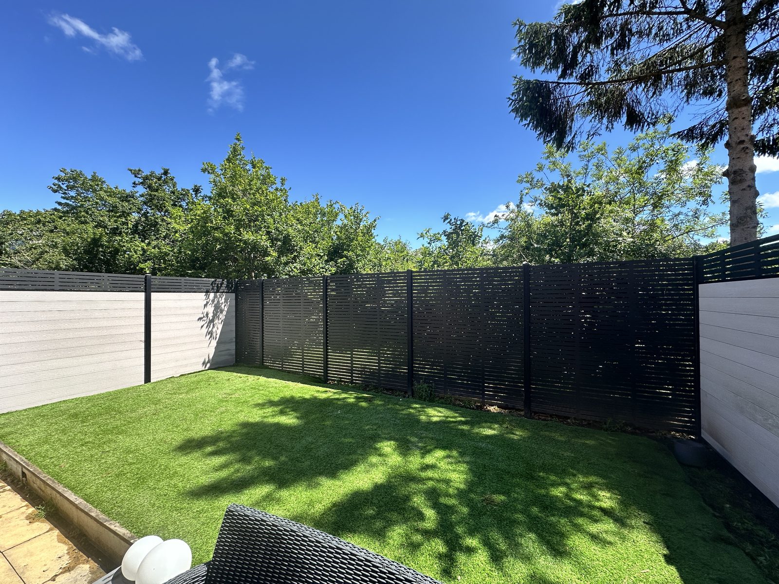 Composite fencing enclosing a lawned garden under a blue sky