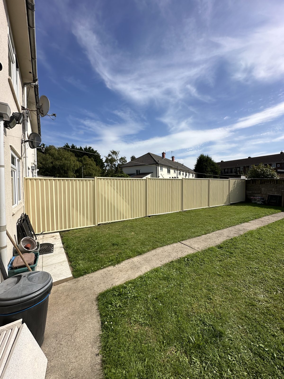 After: a run of cream metal fencing manufactured from Colorbond steel along the garden boundary