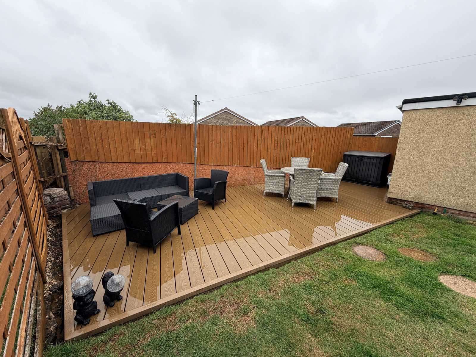 Oak-effect composite deck spanning a back garden with a seating area