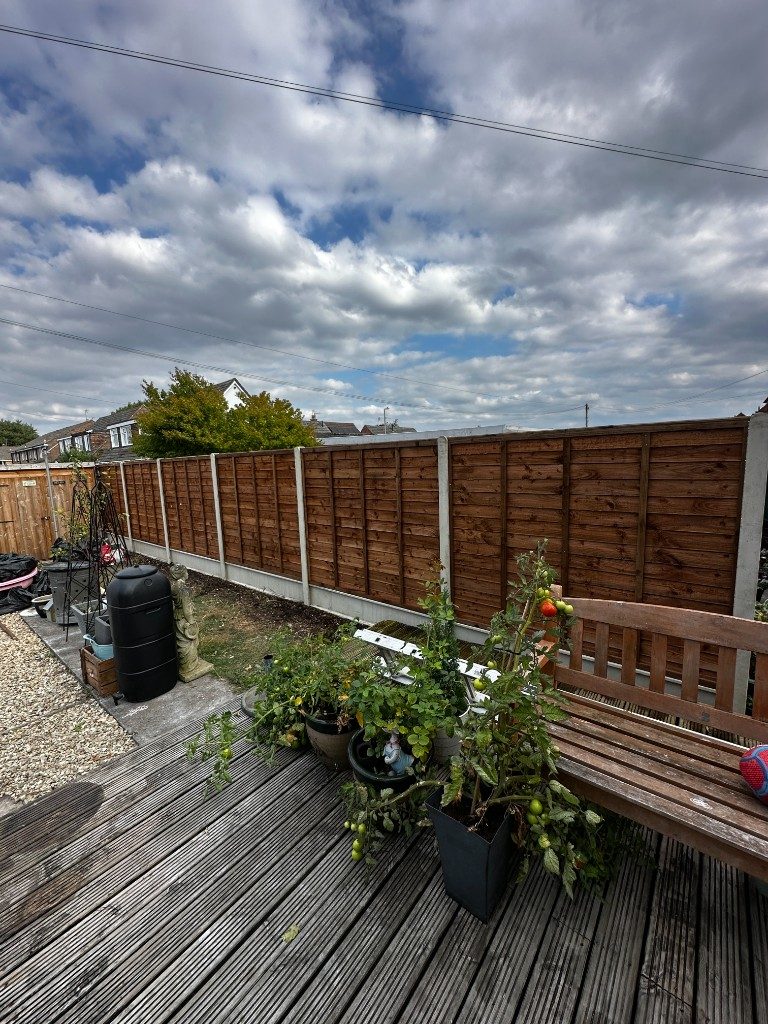 Timber featheredge fencing behind a raised timber deck with a bench and potted plants