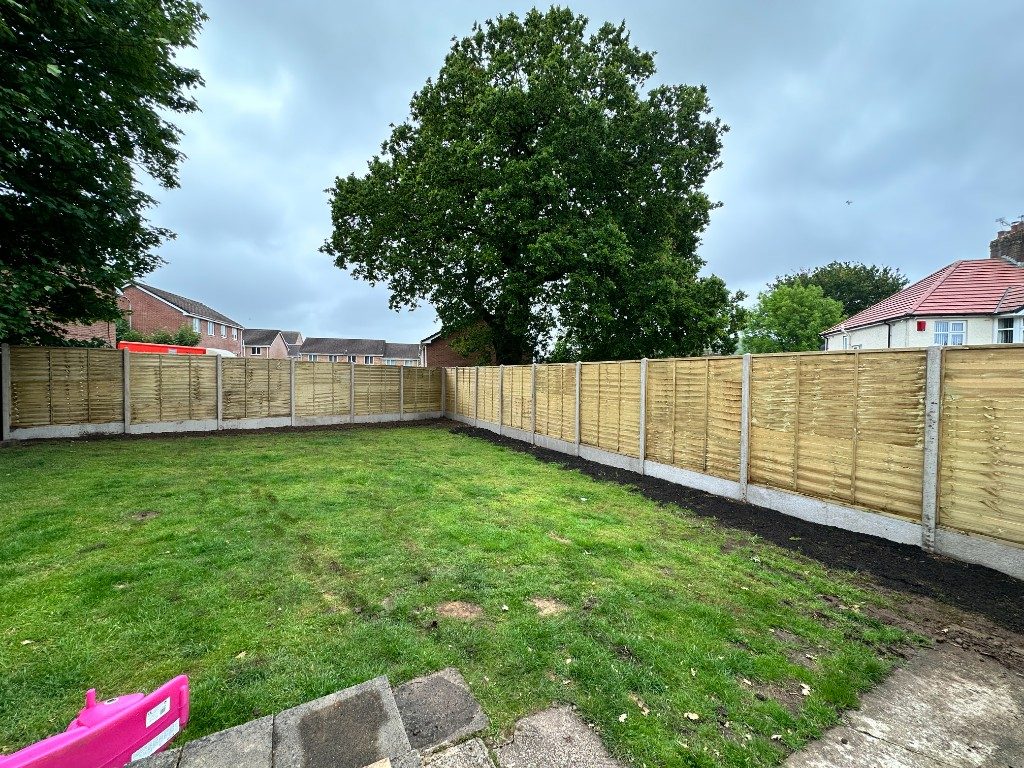 Timber featheredge fencing enclosing a lawned garden with a large tree behind