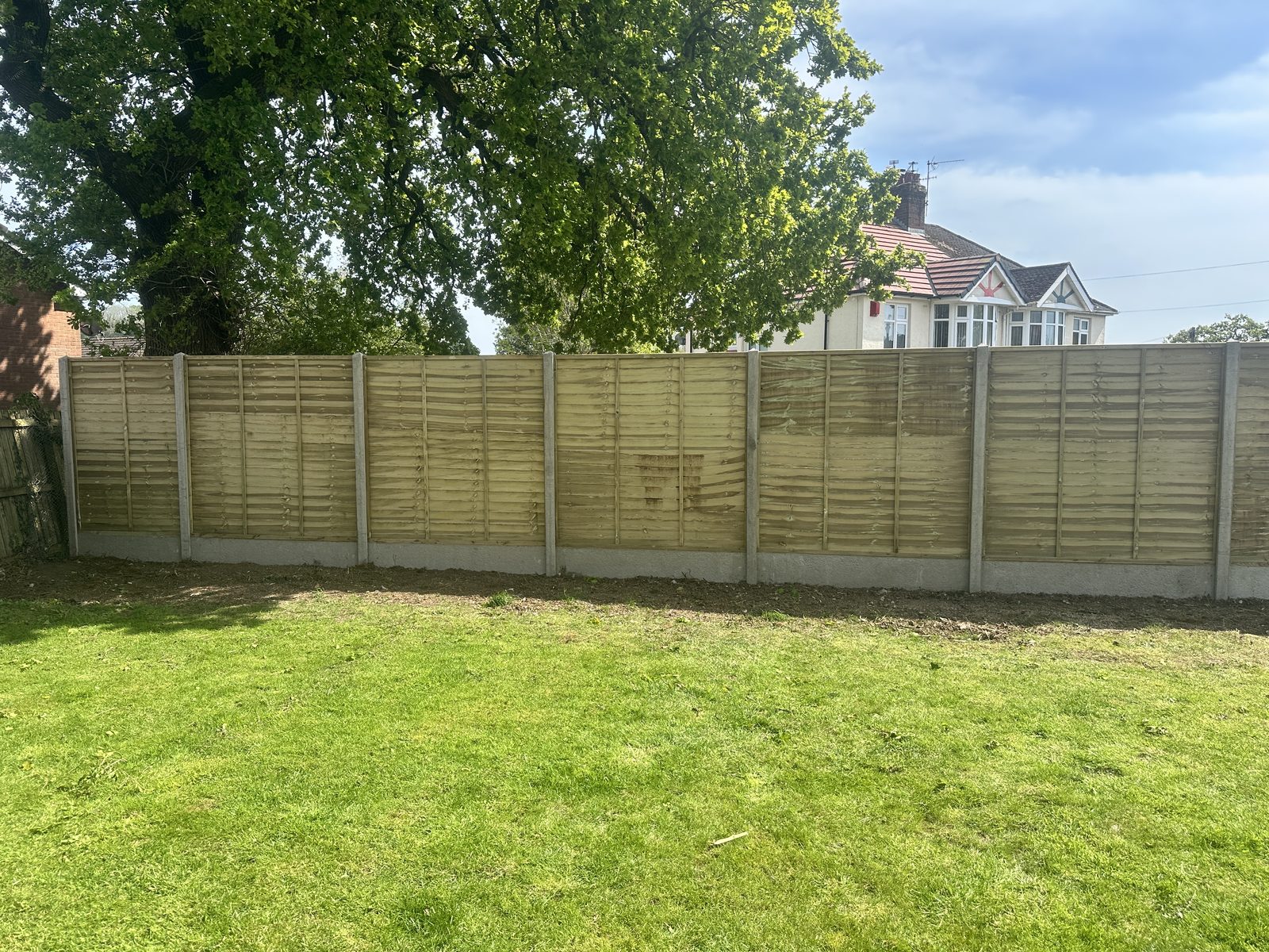 Newly installed timber featheredge fencing with concrete posts and gravel boards along a garden boundary
