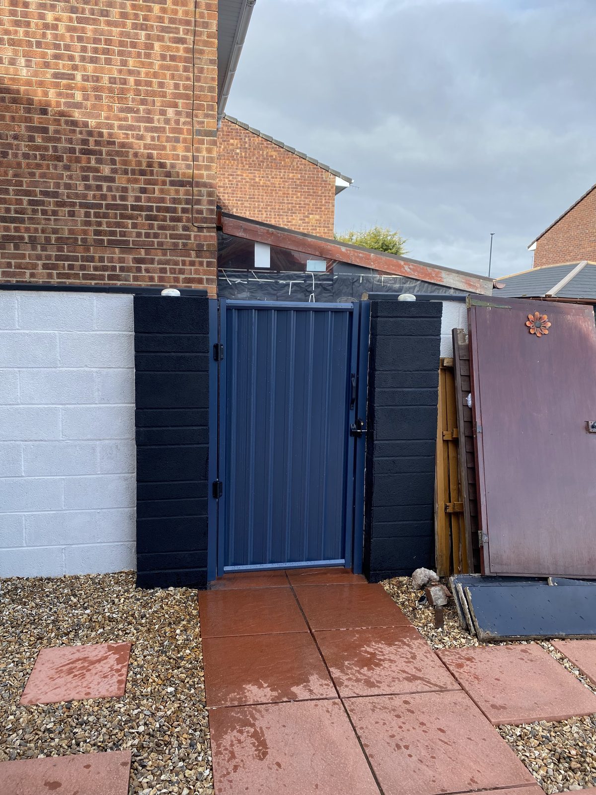 A navy blue metal side gate fitted between rendered block pillars