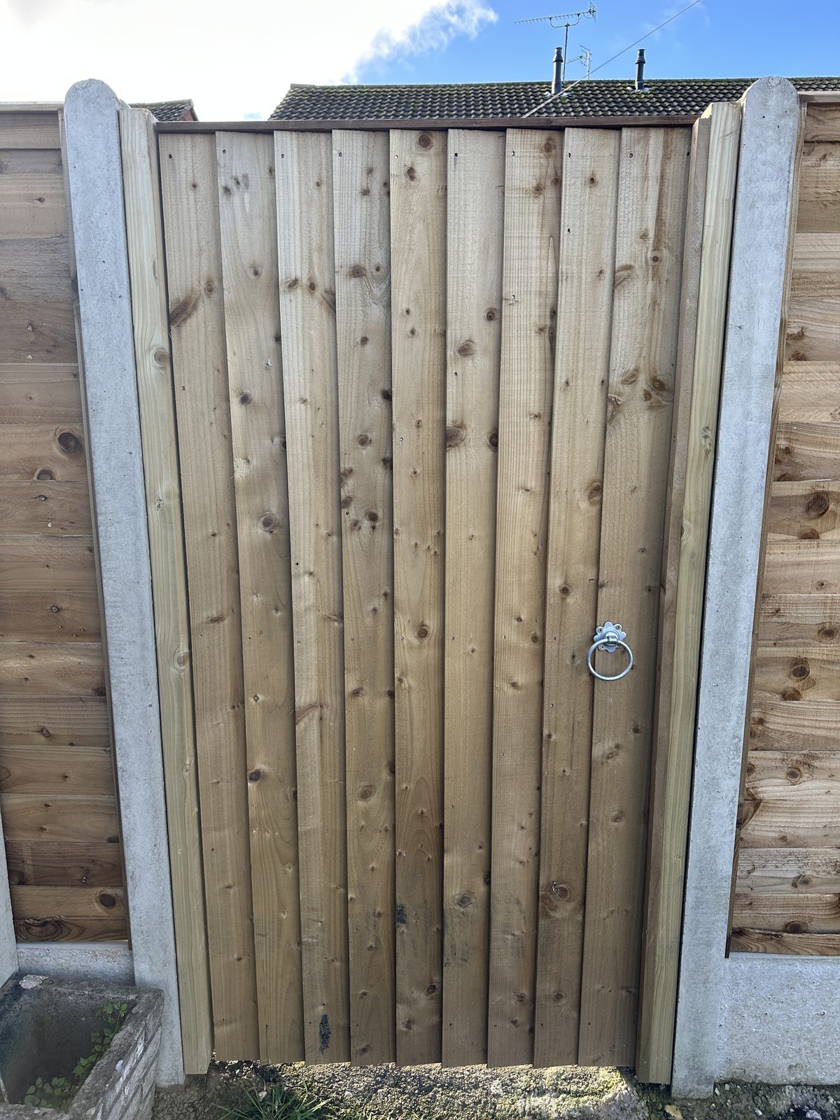 A new timber featheredge side gate hung between concrete posts