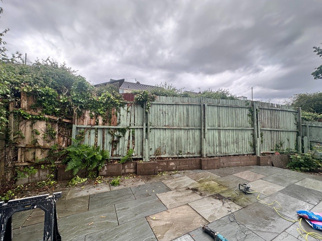 Before: an old, weathered green-painted timber fence overgrown with ivy beside a sandstone patio
