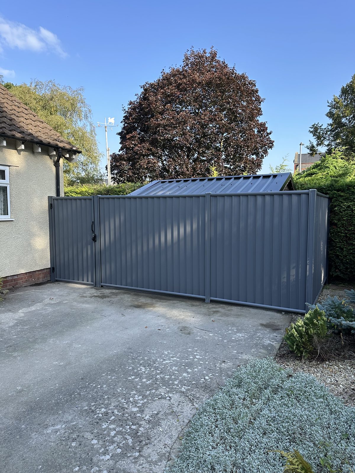 After: the same driveway secured with grey metal fencing and a matching gate manufactured from Colorbond steel