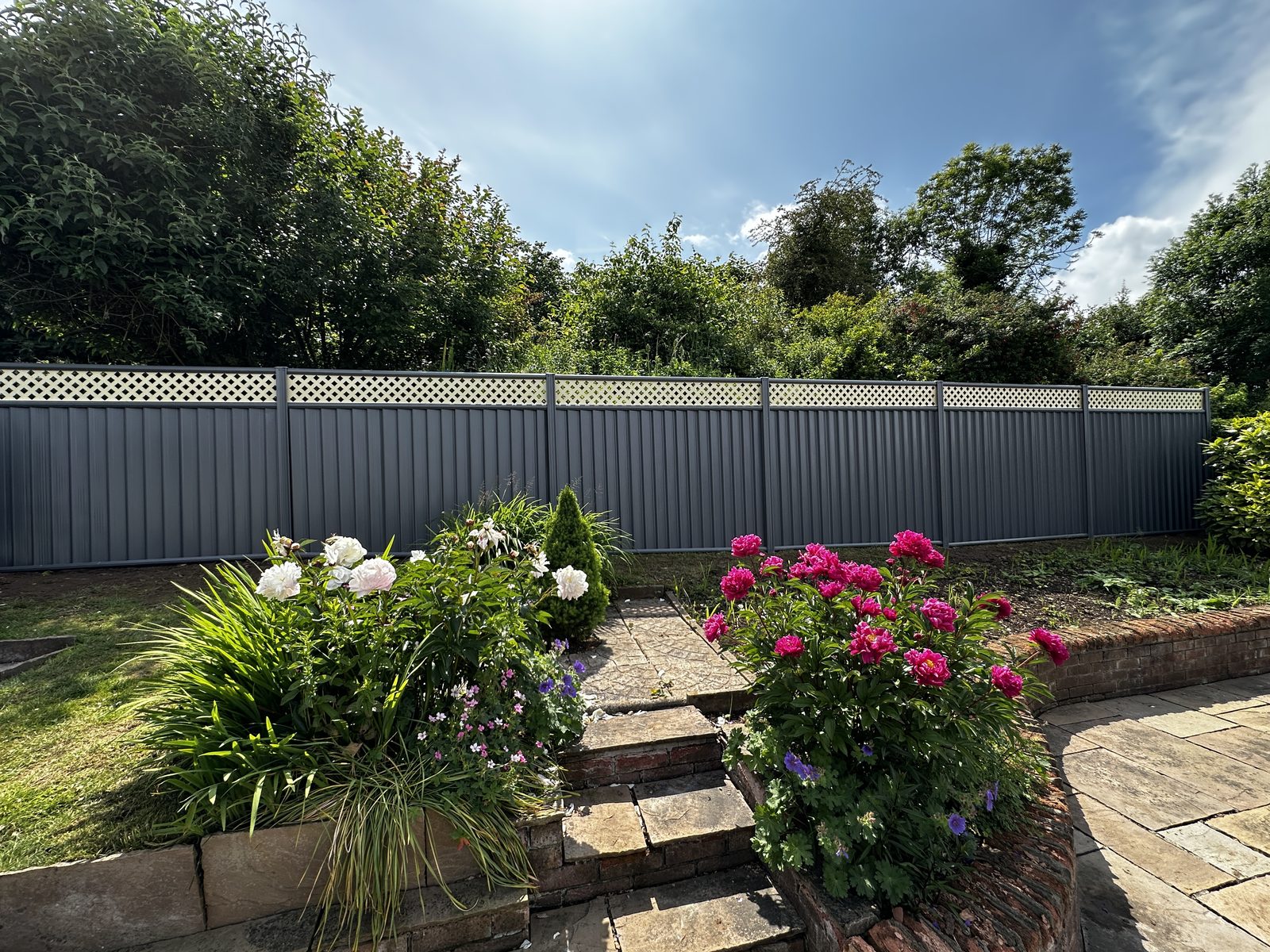 Anthracite metal fencing beside a patio and flower border