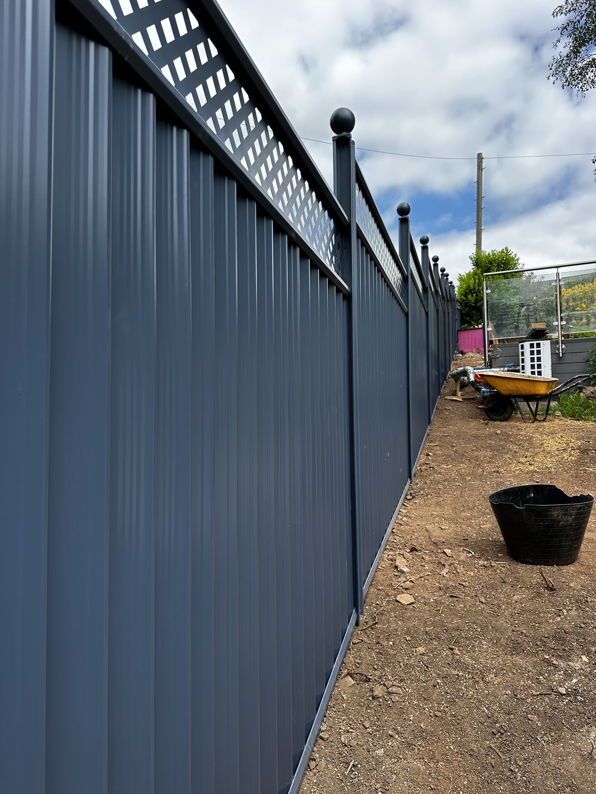 A long run of anthracite metal fencing with a lattice top