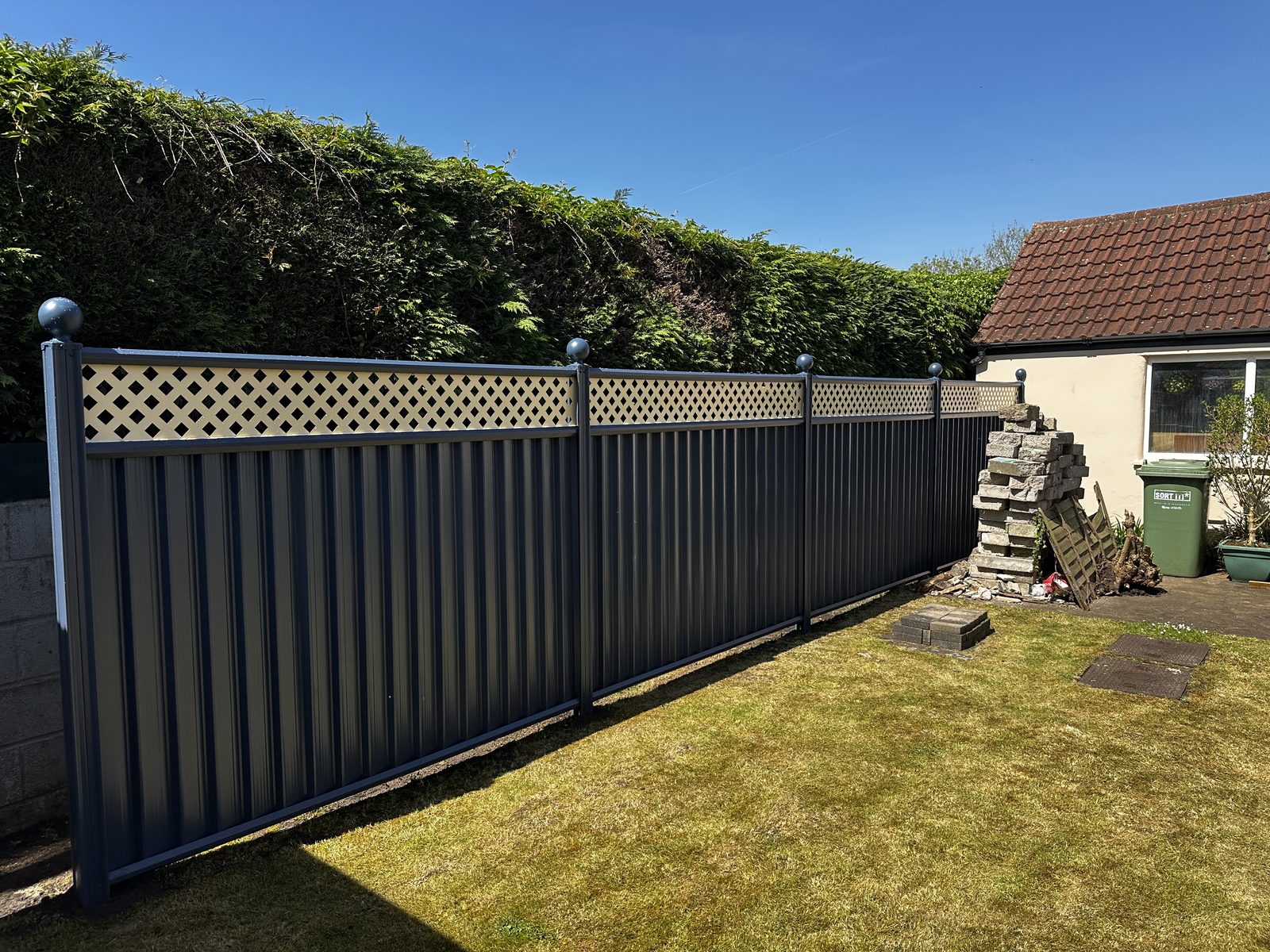 Navy metal fencing with a lattice top along a lawn