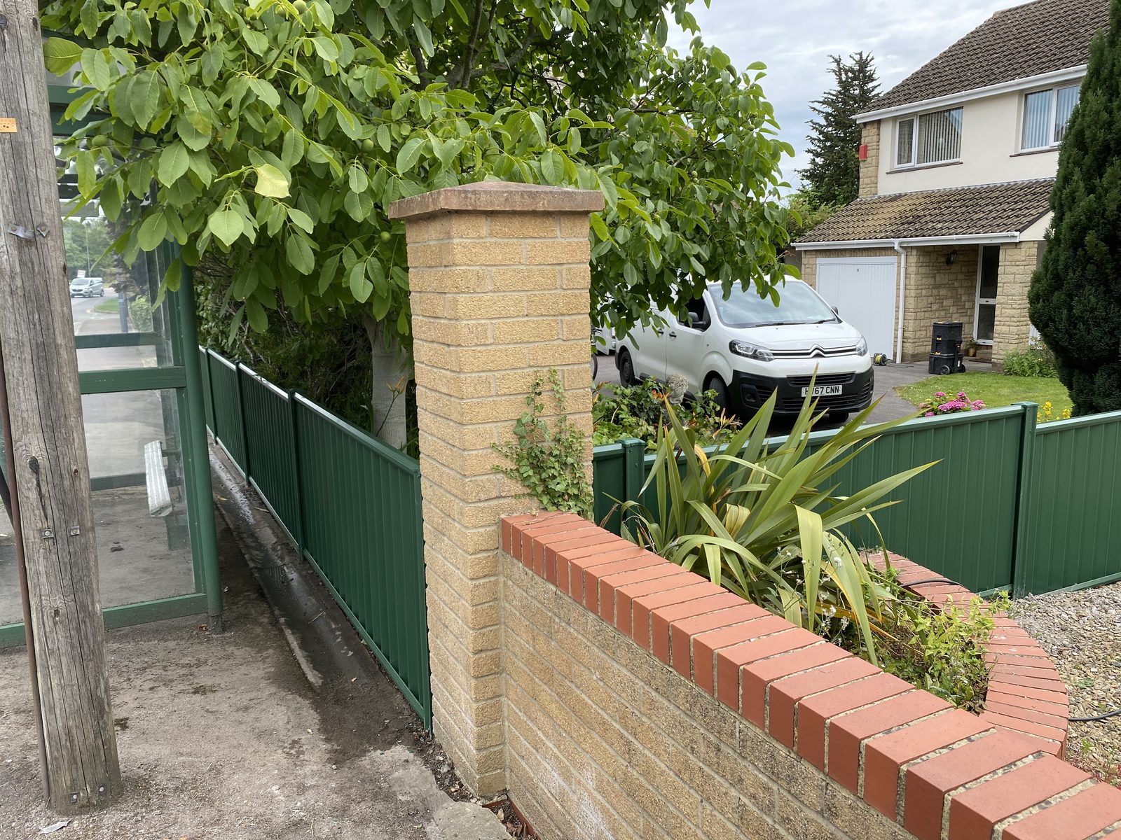 Green metal fencing set on a brick wall beside a path