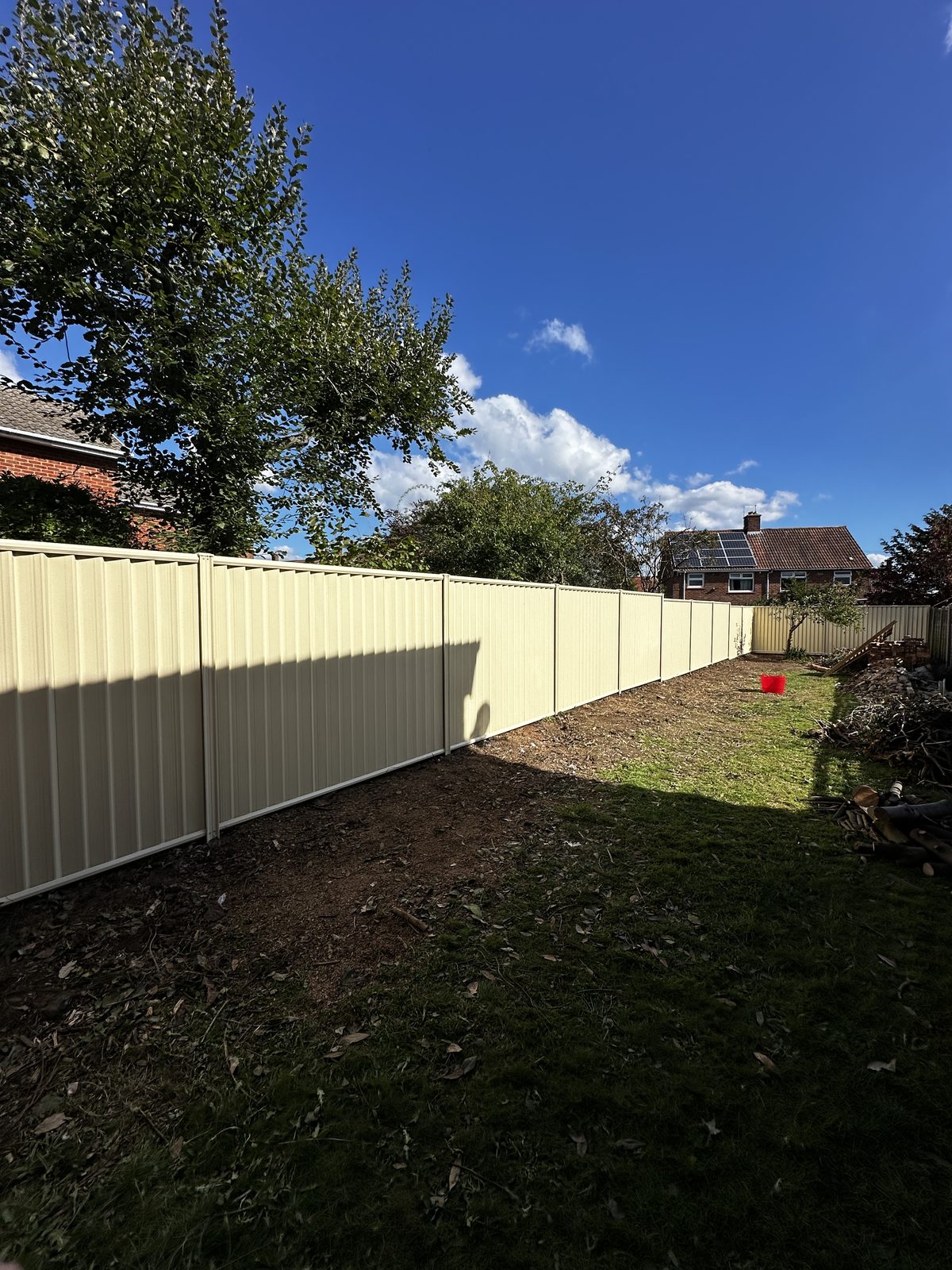 Cream metal fencing along a lawn under a blue sky