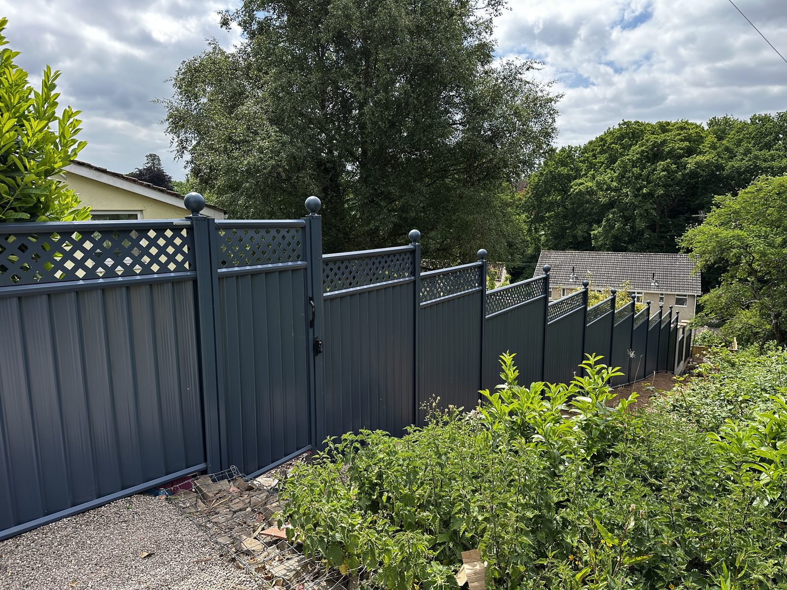 Anthracite metal fencing and a gate beside a planted border