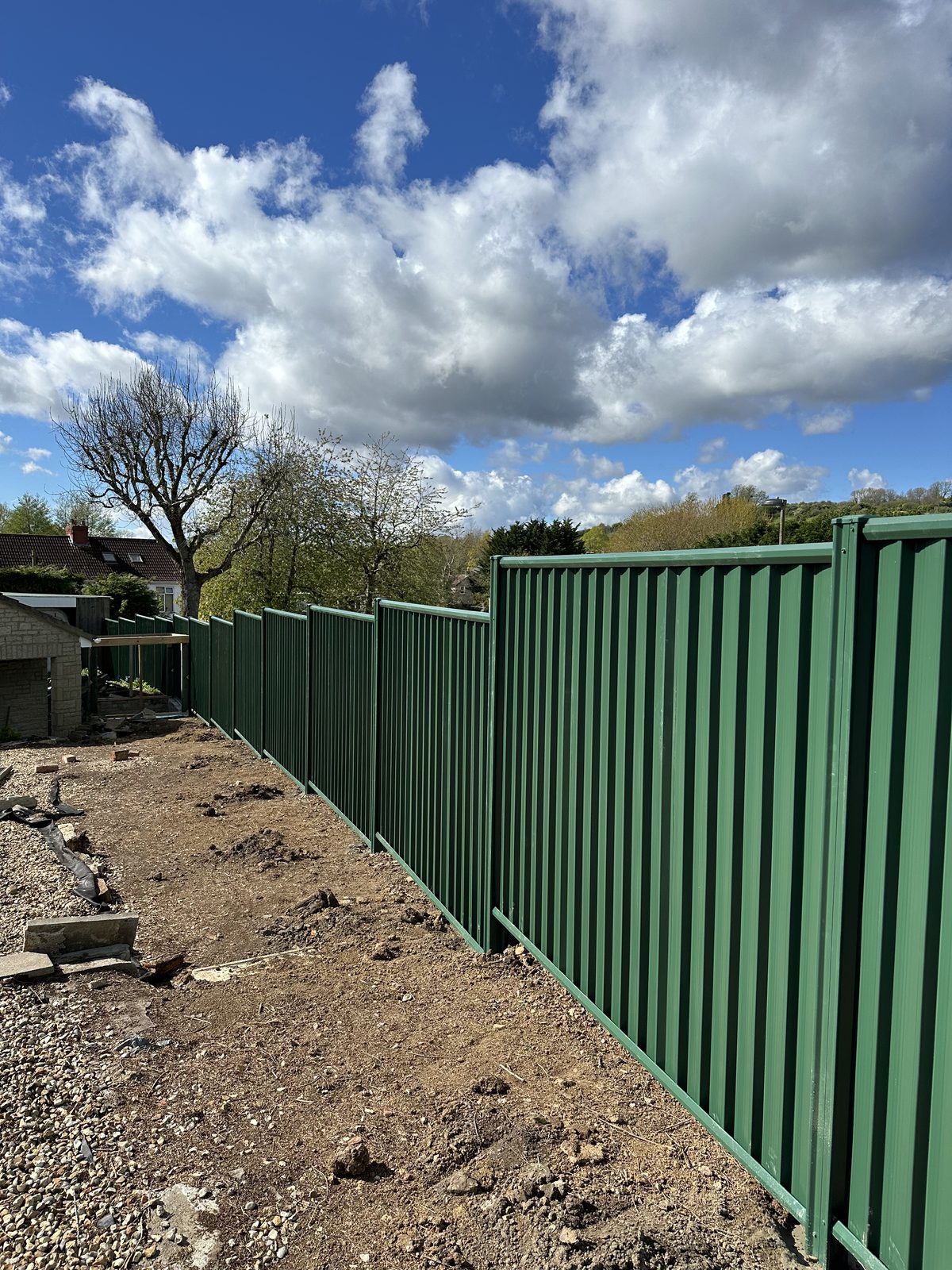A fresh run of green metal fencing under a blue sky