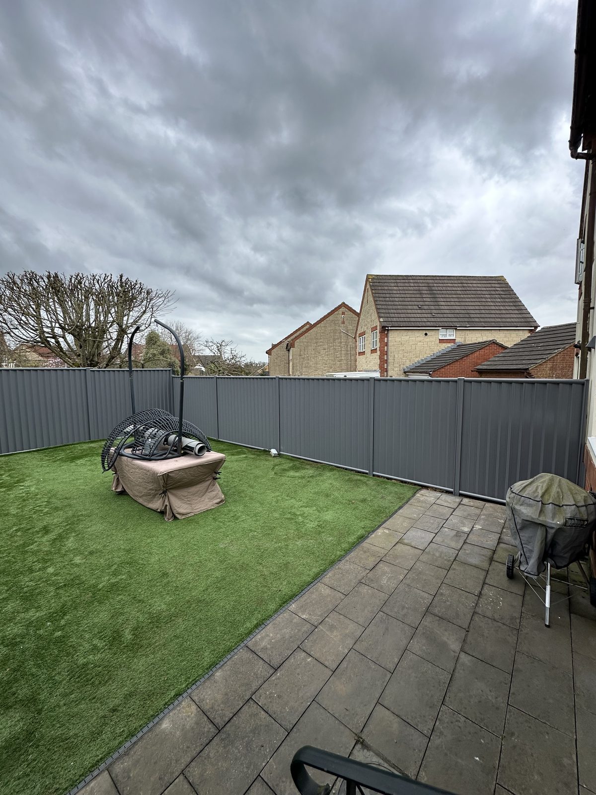 Anthracite metal fencing along a lawn with a patio seating area
