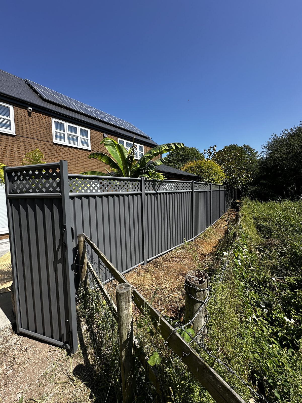 Anthracite metal fencing along a sloping boundary