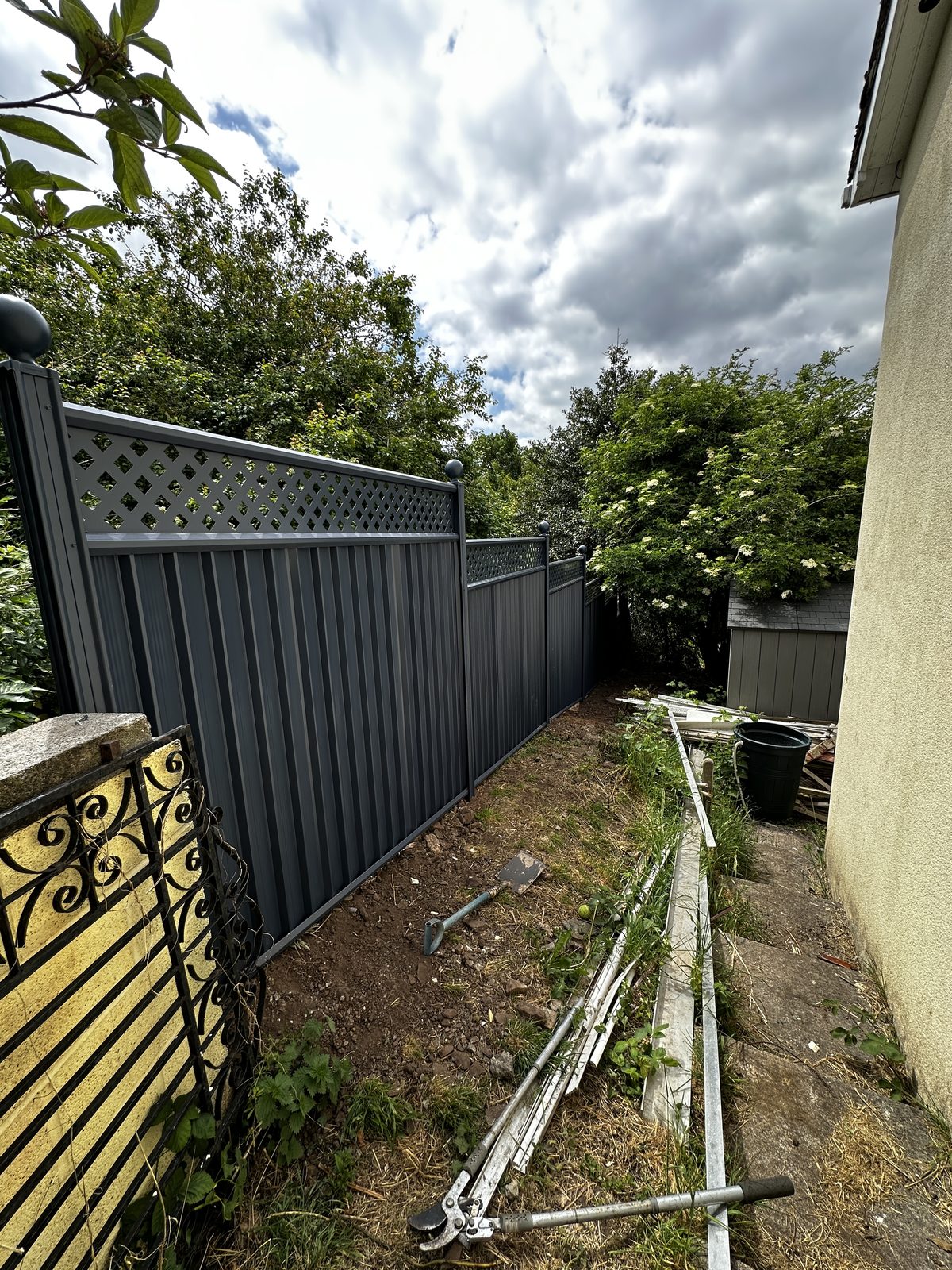 Anthracite metal fencing with a lattice top along a side passage
