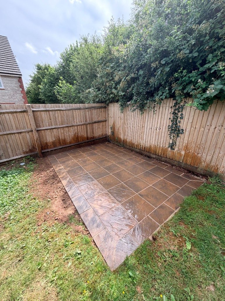 After: a neat riven sandstone patio laid into the corner against the fence