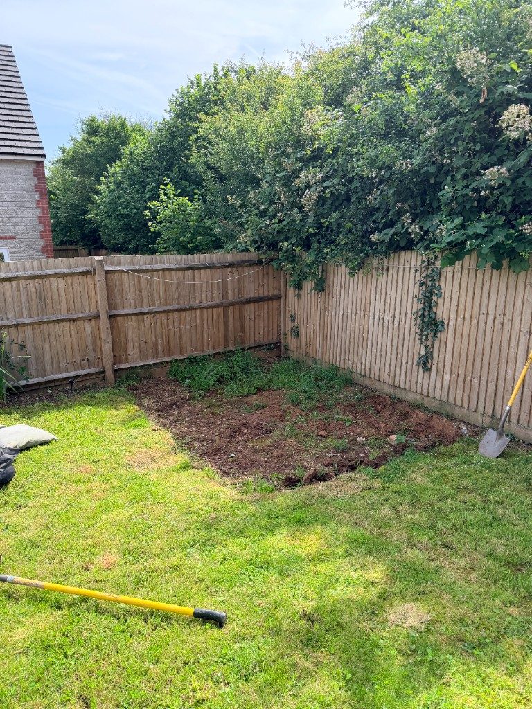 Before: a cleared, weed-strewn corner of a garden dug out ready for paving