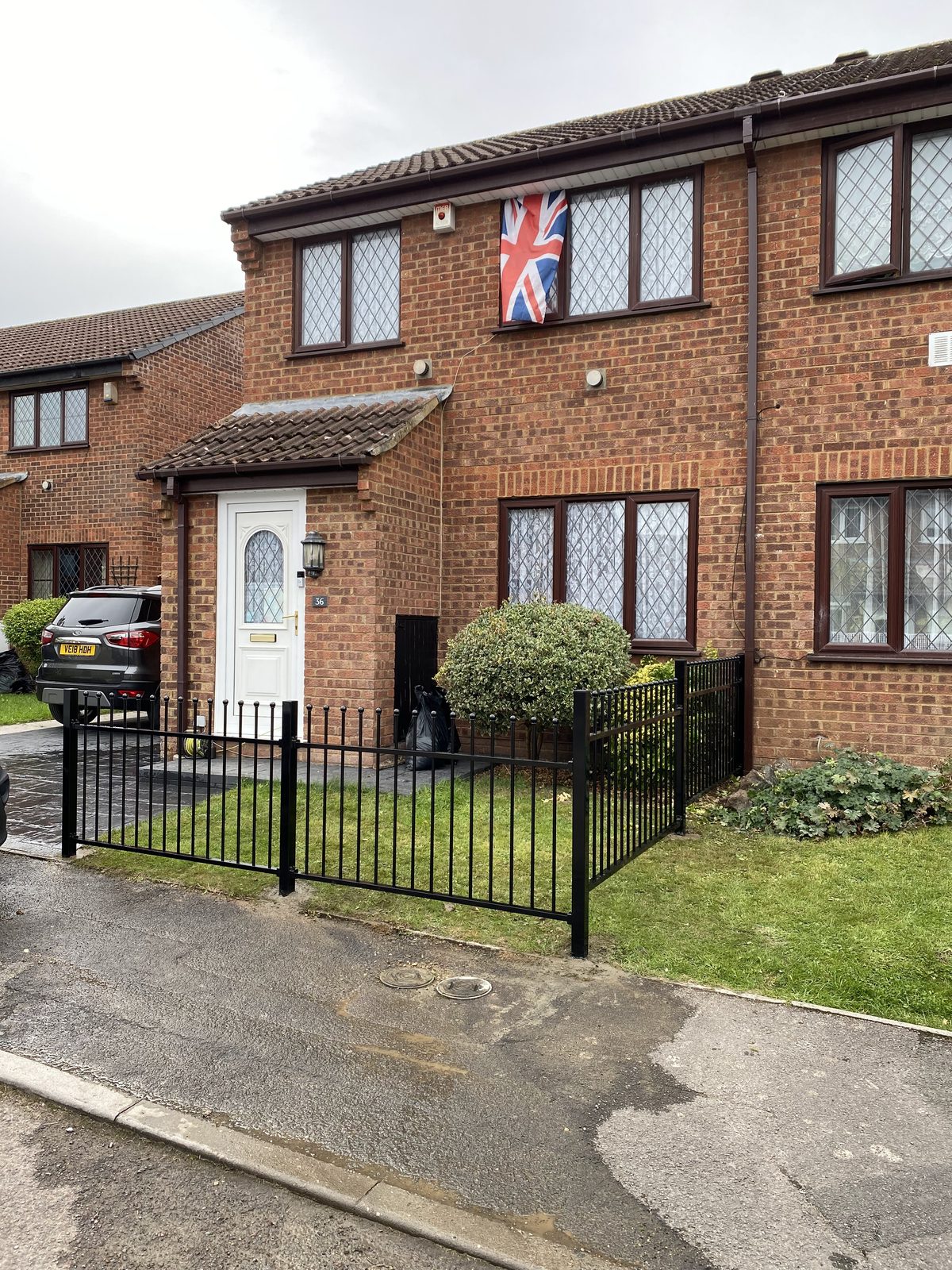 Black metal railings and gate in front of a brick home