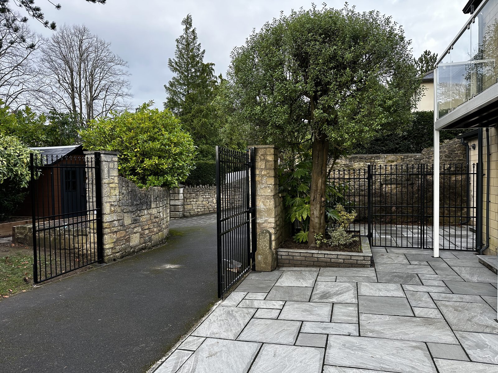 Black metal railings and a matching gate along a paved driveway boundary