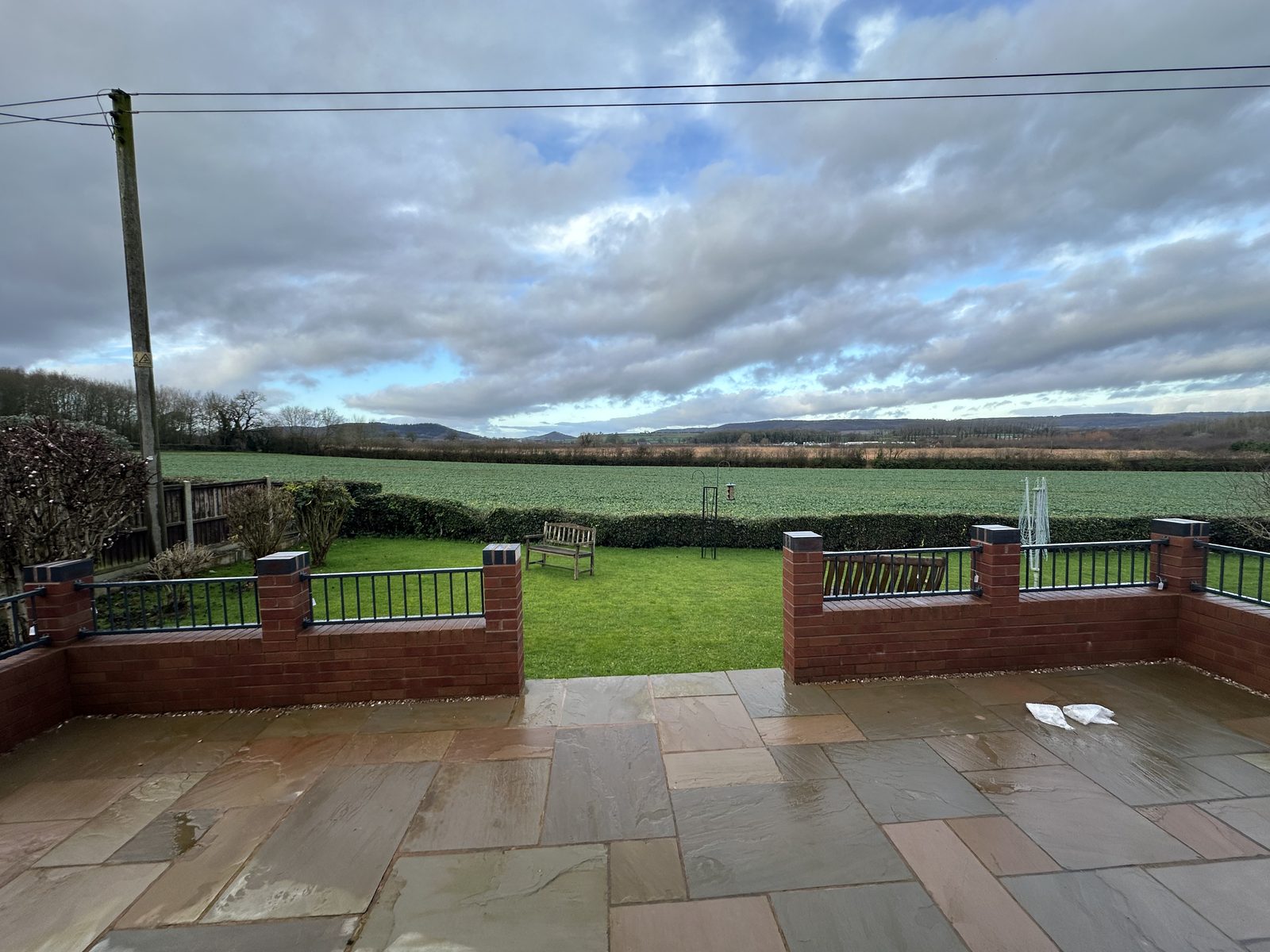 Black metal railings on a low brick wall overlooking open countryside