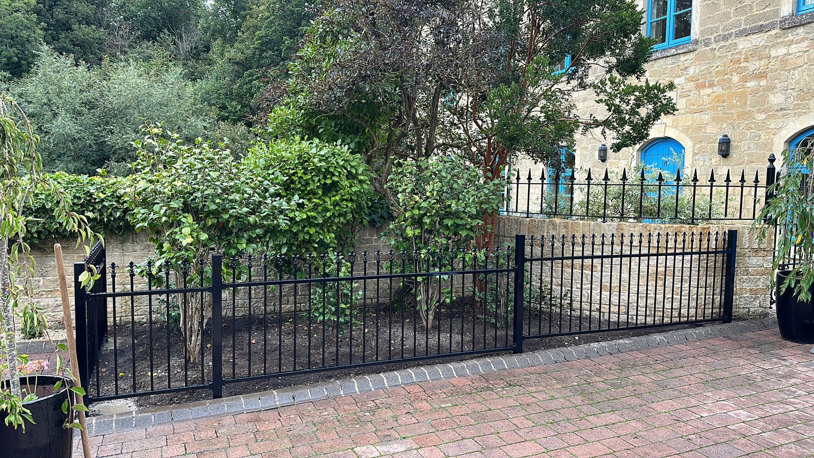 Black metal railings on a low wall along a front garden