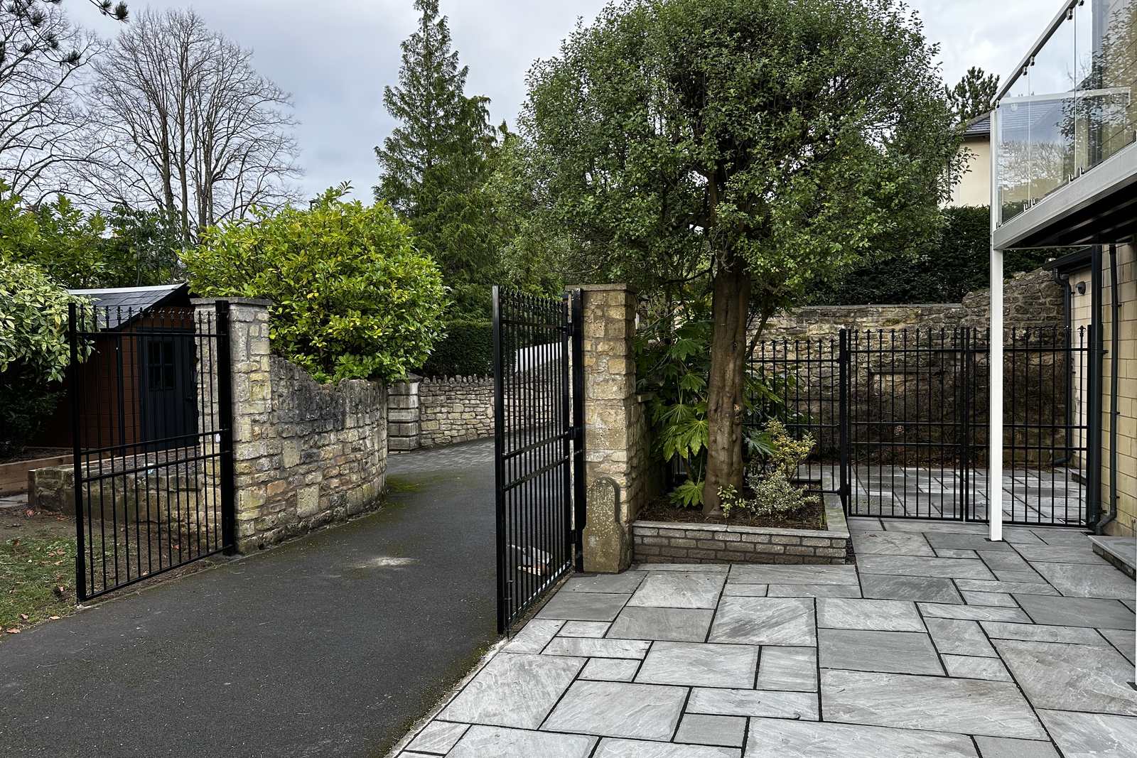 Black gates and railings set between stone walls.
