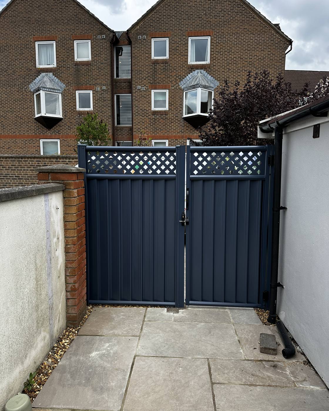 Blue metal fence panel and gate with matching blue decorative lattice.