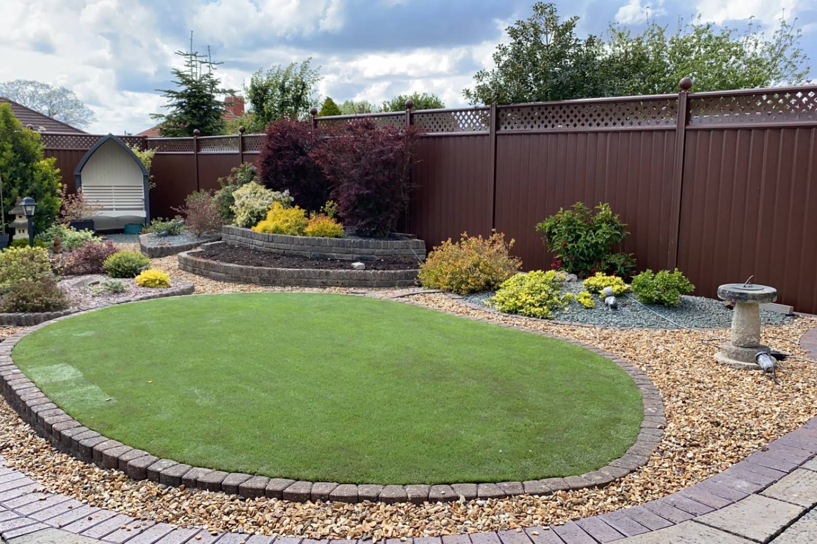 A landscaped garden framed by a brown boundary fence.