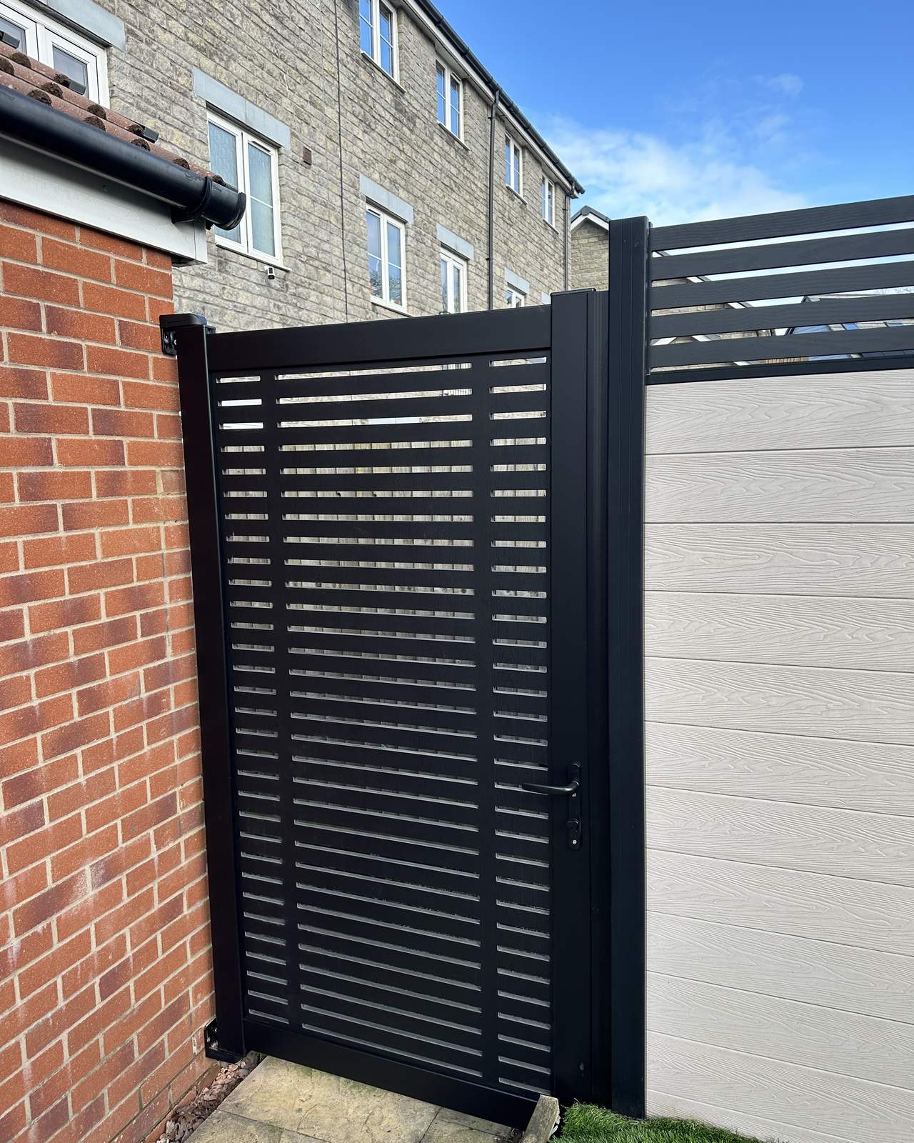 Composite pedestrian gate with matching garden boundary panels.