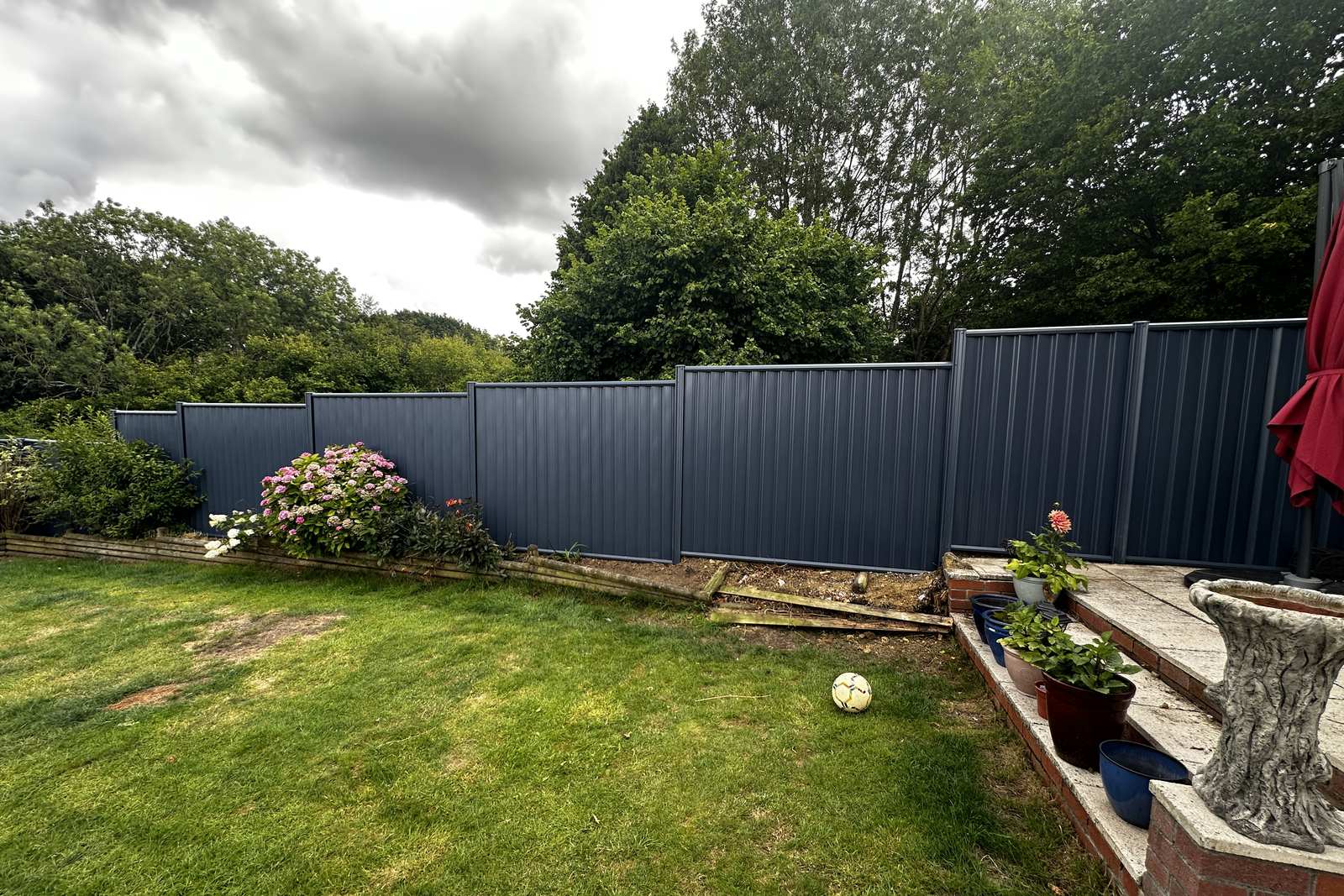 Blue metal fencing along a rear garden boundary.