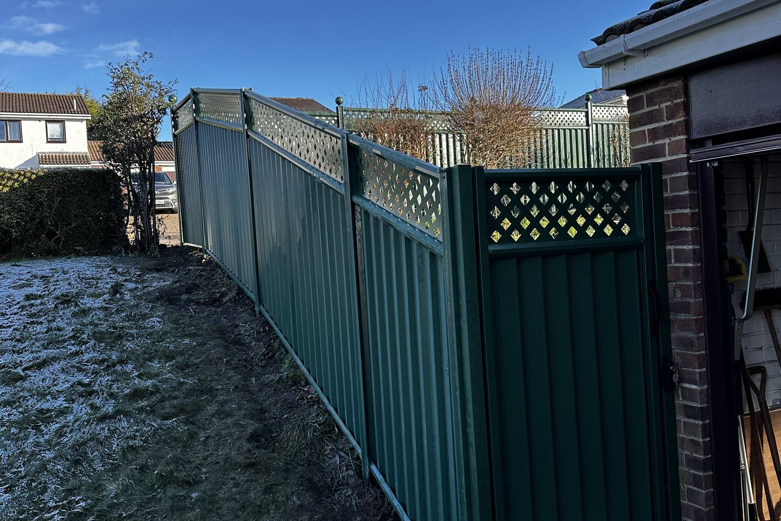 Replacement green metal boundary fence in place of a failed timber run.
