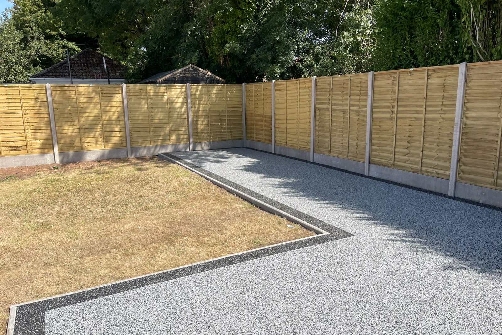 Timber-panel fencing with concrete posts beside new resin-bound surfacing.