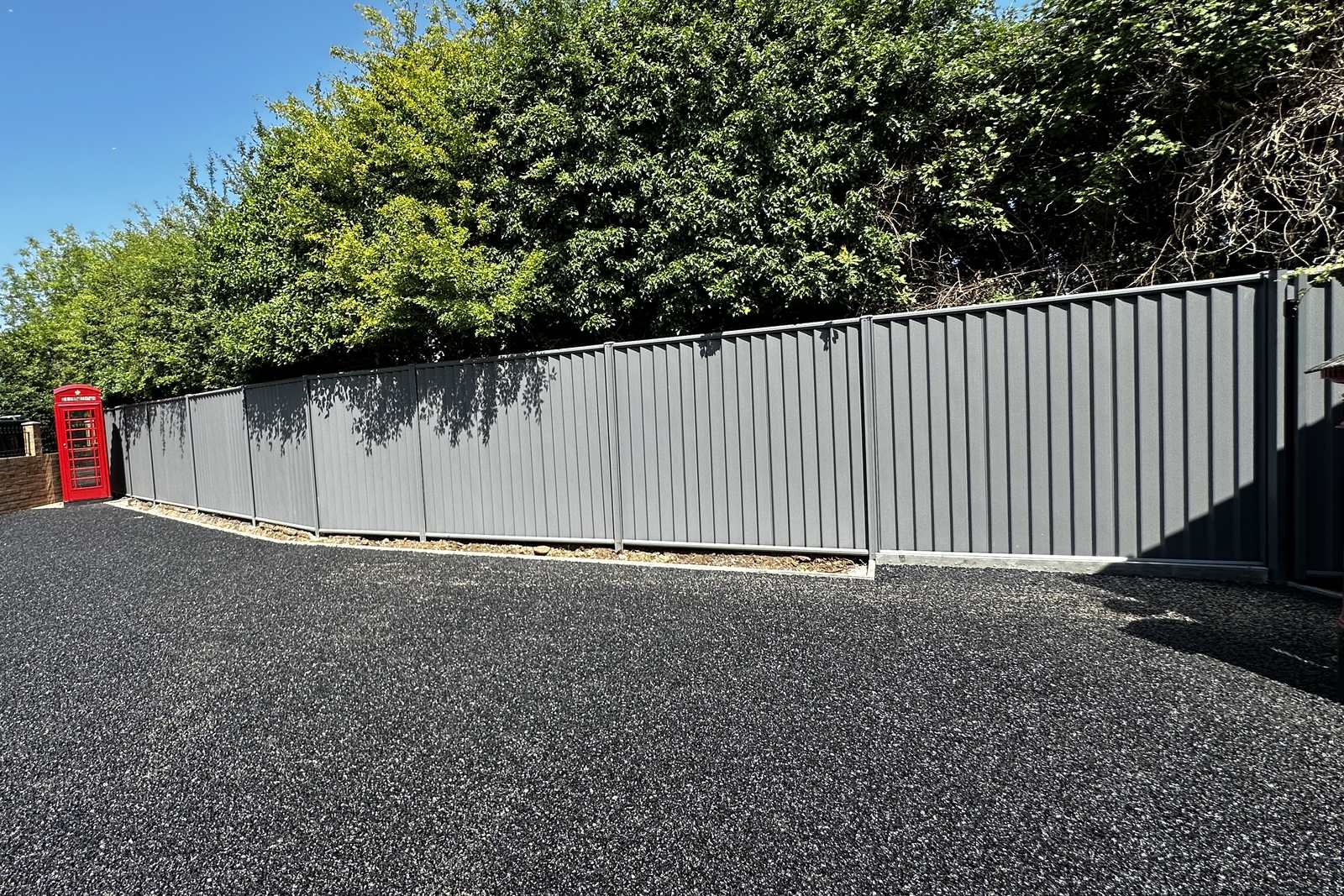 A long grey metal boundary run beside a surfaced drive.