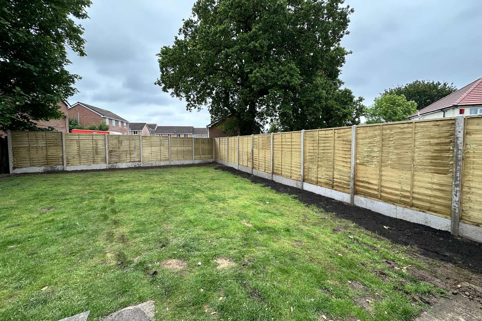 Pale timber boundary fencing beside a lawn.