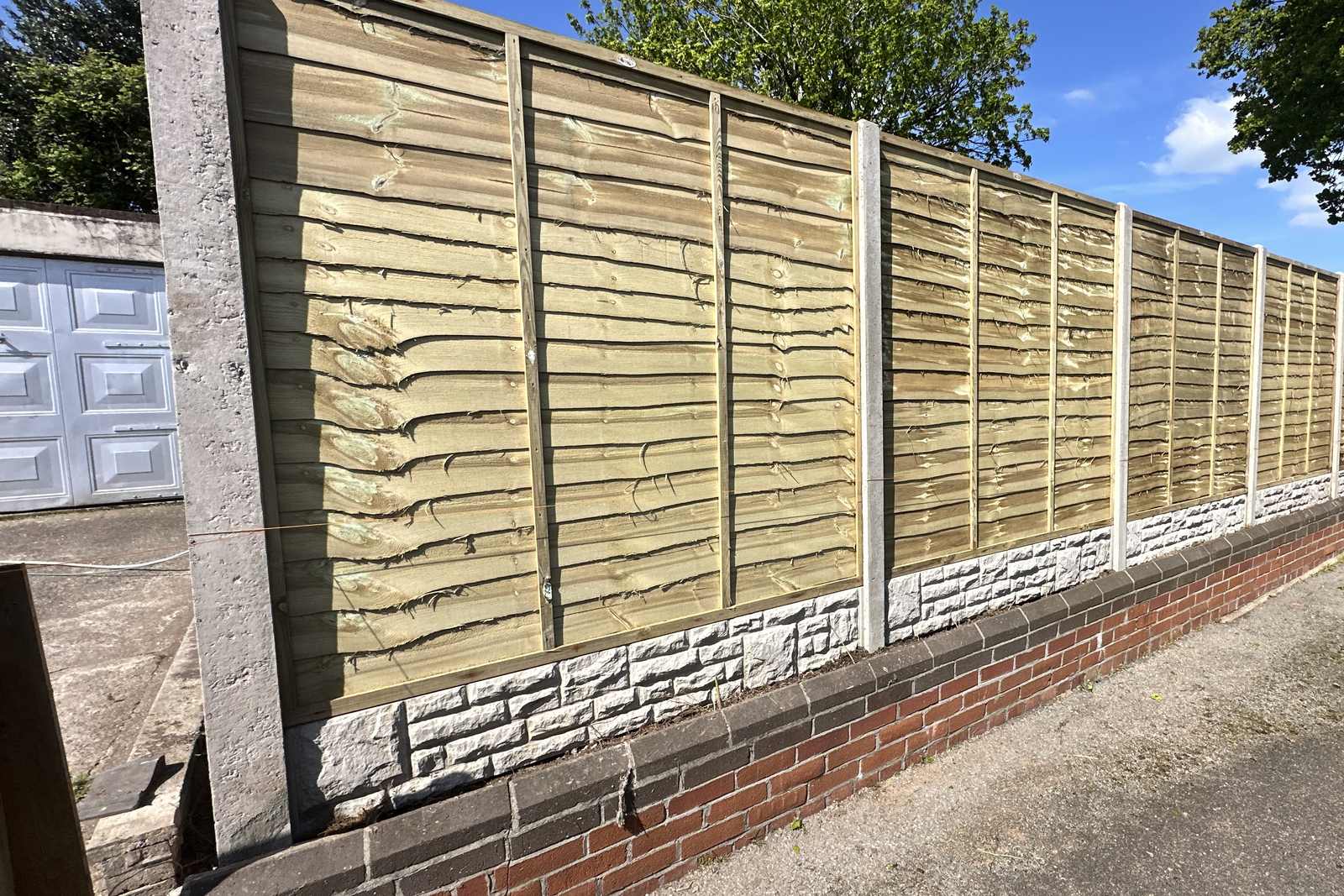 Timber fence panels fitted above a brick garden wall.