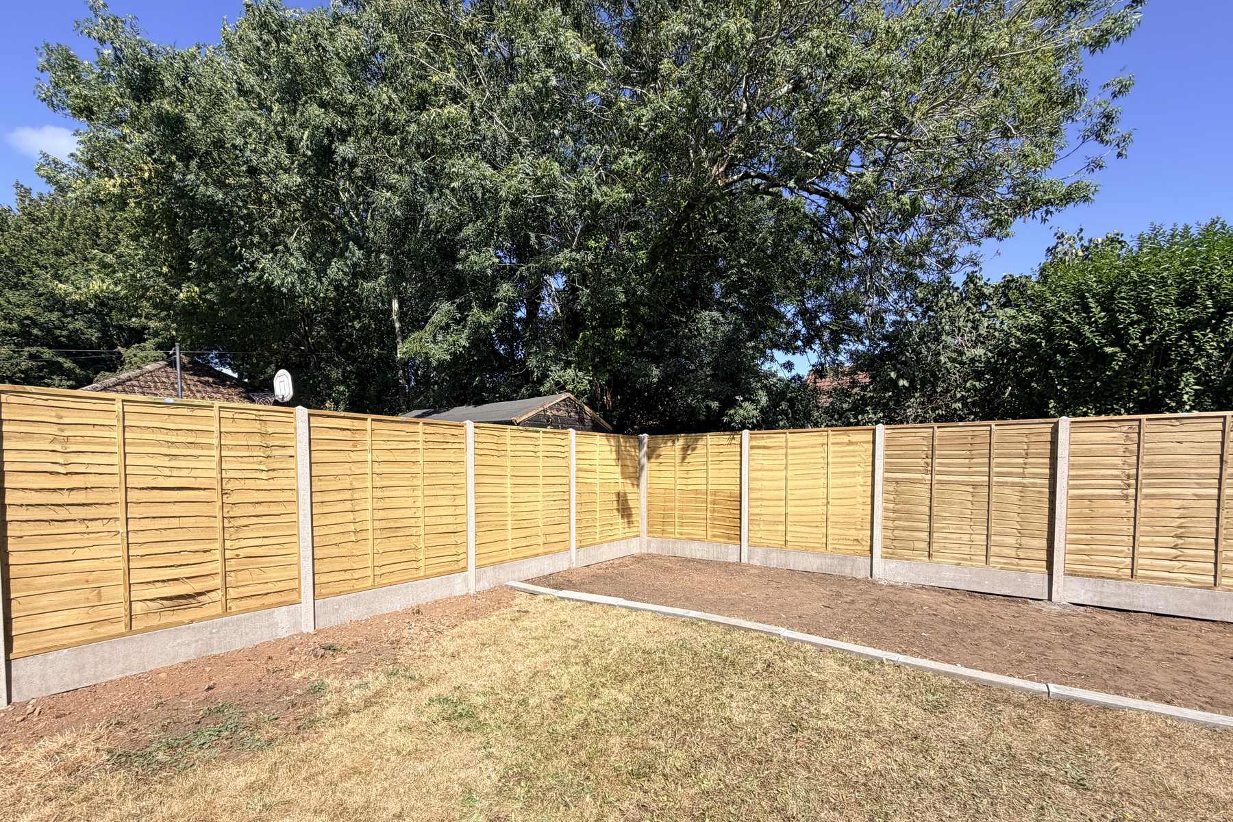 New timber panel fencing with concrete posts enclosing a garden.